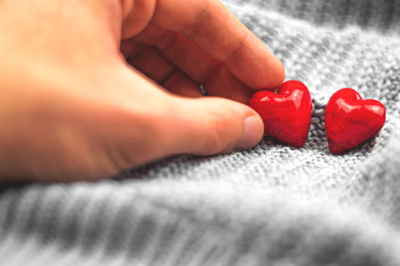 Valentine's Day composition, red hearts and hand of boy, man pick up heart, couple love concept photoの写真素材