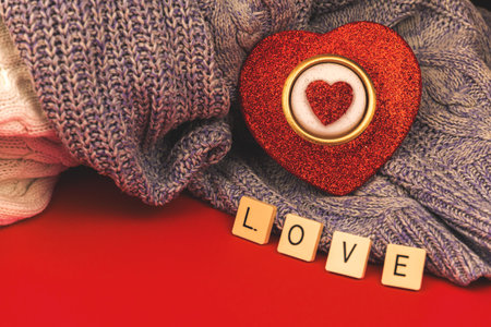 Candle in form of red heart, Valentine's day concept and greeting card with love word on red background with knintted warm and cozy sweaters photoの写真素材