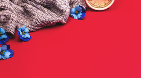 Spring fresh and cozy background with flowers, alarm clock and knnited sweaters, concept banner photoの写真素材