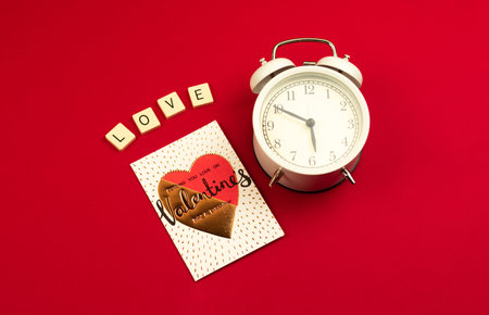 Valentine's Day greeting card concept on red, love word, letters, heart and alarm clock at morning for couple, photoの写真素材