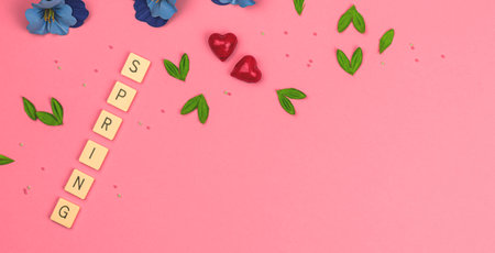 Flat lay spring background with decorative flowers and leaves, banner on a bright vibrant pink, copy space photoの写真素材