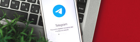 KHARKOV, UKRAINE - January 26, 2021: social network telegram on Apple iPhone, flat lay banner for news of social networks, copy space and workplace with laptopのeditorial素材