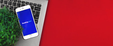 Kharkov, Ukraine - 26 January, 2021: flat lay banner with travel app Booking.com screen on a Apple iPhone smartphone, copy space and template, workplace photoのeditorial素材