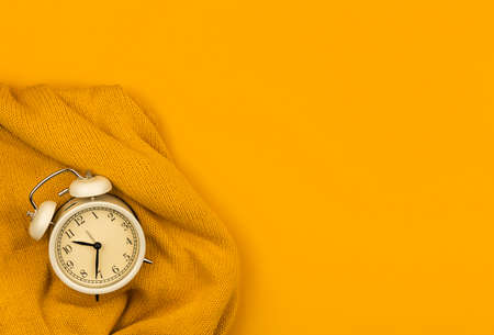 Flat lay spring background with sweater and alarm clock, copy space banner and yellow table, desk, composition of workplace photoの写真素材