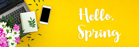Hello Spring background with text inscription, holiday workspace with bouquet of flowers, yellow desktop photoの写真素材