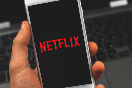 Kharkov, Ukraine - February 22, 2021: man holding Apple smartphone with Netflix application, logotype of streaming service close up photoのeditorial素材