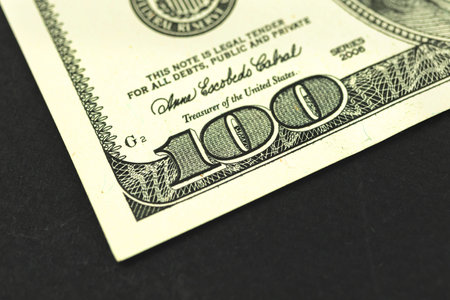 Fragment of hundred dollar bill bankmote on macro, close up on a black background