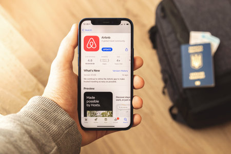 Kharkov, Ukraine - March 9, 2021: Airbnb app on the screen, man is search for the house to live in...
