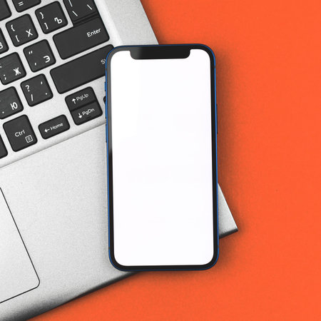 Business mockup with mobile phone with blank white screen, laptop on background