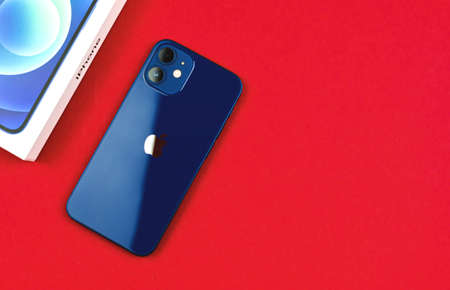 Kharkov, Ukraine - March 12, 2021: Close-up of backside of iPhone 12 Paciffic Blue color on red background, copy spaceのeditorial素材