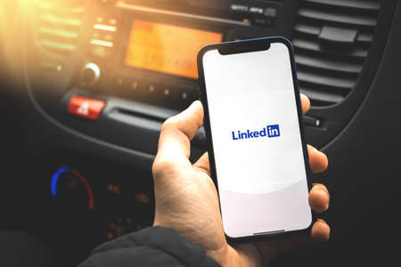 Kharkov, Ukraine - March 17, 2021: Business man holds smartphone with linkedin mobile applicationのeditorial素材