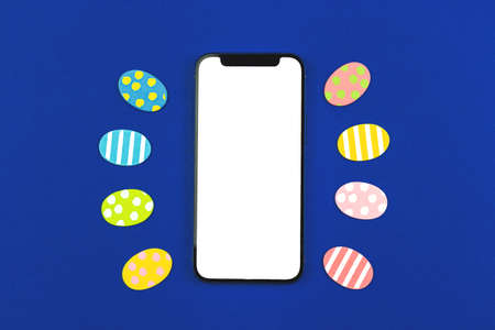 Happy Easter mockup, smartphone with blank white screen and holiday easter eggs decorationsの写真素材