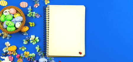 Easter greeting card concept with blank notebook, banner with blue bakcground and spring decorationの写真素材