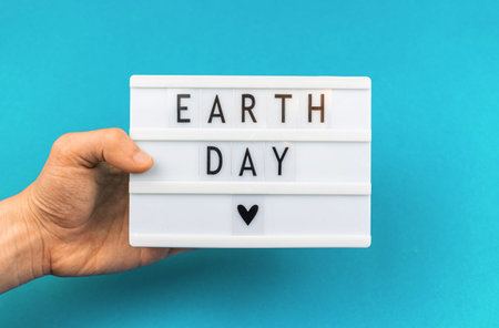 Earth Day lettering background, man holding lightbox with text message, environment protection...