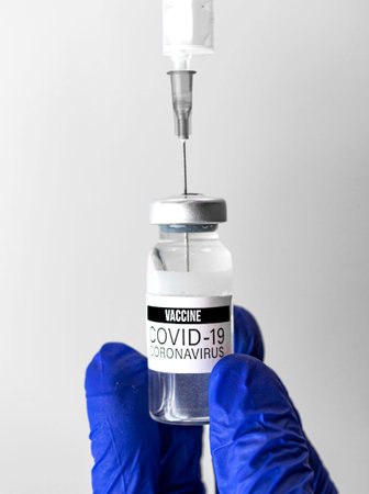 Doctor in blue gloves use covid-19 vaccine by injection syringe inside the bottle