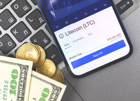 Buy Litecoin button on the screen, mobile phone with crypto currency trading app close-up