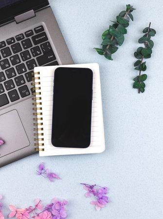 Elegant workspace concept background with laptop, smartphone, notepad and beautiful flowers, top...