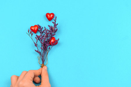 Concept of chatiry and helping hand, save life and world heart day background, man hand holds a bunch of flowers with red hearts like family treeの写真素材