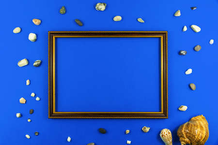 Summer flat lay composition with old wooden frame and seashell on a blue background, copy space and top viewの写真素材
