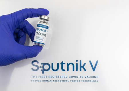 Kharkov, Ukraine - April 18, 2021: Sputnik V vaccine in a hand, blue gloves, logo on a white background, vaccination concept photoのeditorial素材