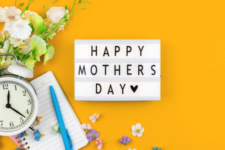 Happy Mothers Day flat lay card concept, yellow background with spring decorative flowers, top view,...