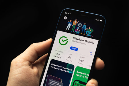 Kharkov, Ukraine - April 20, 2021: Sberbank app close up logo and icon, man uses smartphone with...