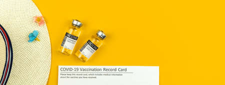Summer vacation during coronavirus, banner with vaccine vials and vaccination record card, straw hat on a yellow background, flat lay, top view and copy spaceの写真素材