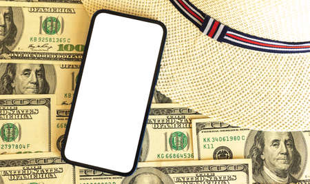 Expensive travel mockup with mobile phone screen, summer vacation and trip concept with background of straw hat and bunch of US dollar money, copy spaceの写真素材