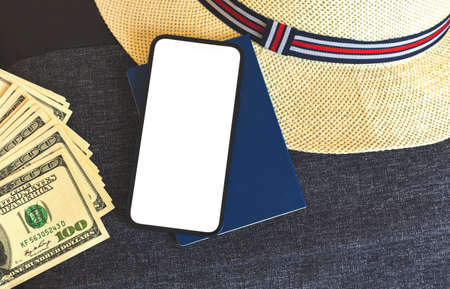 Summer travel and vacation mockup concept with mobile phone, money, passport and tropical straw hat, top view, traveler preparation photoの写真素材