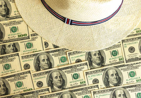Expensive travel background, concept of summer vacation with hundreds of US dollars and straw hat on background, top view photoの写真素材