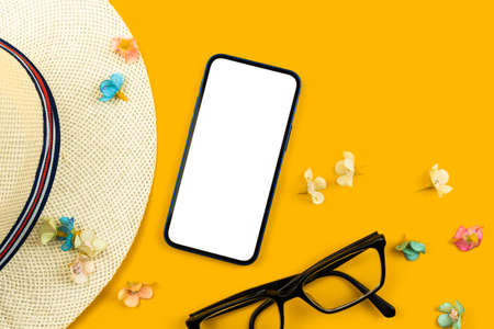 Travel and summer vacation flat lay mockup template with blank white screen, straw hat, smartphone and glasses on yellow background, tourism conceptの写真素材