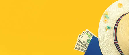 Top view of traveler accessories on bright yellow background, summer vacation concept with straw hat, tropical flowers and money for trip, copy spaceの写真素材