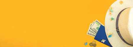 Summer holiday, vacation, travel concept banner on orange background, straw hat, passport, money and tropical flowers, top view and flat layの写真素材