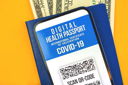 Certificate of vaccination against COVID-19 coronavirus on the screen of mobile phone close-up, travel and summer vacation concept, top viewの写真素材
