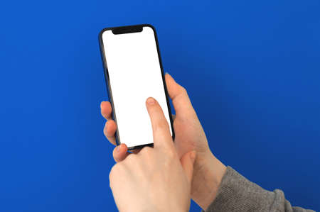 Kharkov, Ukraine - May 5, 2021: Woman hold Apple mobile phone and touch the screen, mockup, blue background photoのeditorial素材
