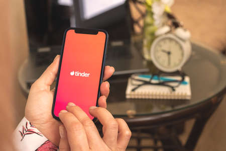 Kharkov, Ukraine - April 27, 2021: Woman hold mobile phone with Tinder app on the screen Apple iPhone 12のeditorial素材