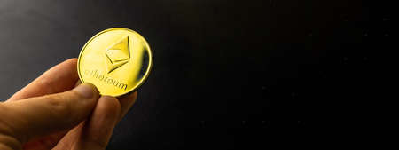 Business ethereum coin banner photo with copy space, golden coin in hand, cryptocurrency conceptの写真素材