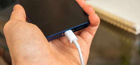 Kharkov, Ukraine - April 27, 2021: Man use lightning connector for charge Apple iPhone 12 Miniのeditorial素材
