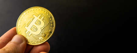 Banner bitcoin in hand on black background, golden crypto coin currency, business and finance concept, copy space photoの写真素材