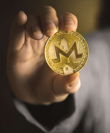 Monero coin in hand close-up view, business background photo of crypto currencyの写真素材