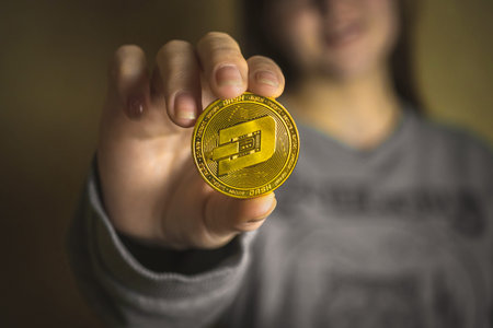 Woman holding a physical dash coin cryptocurrency in her hand, close-up view photo