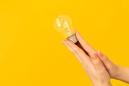 Concept new idea with innovation and creativity, woman hand hold light bulb on orange background