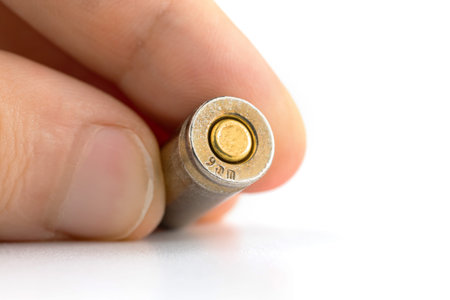 Man holds 9mm bullet close up view with bottom of bullet cartridges on isolated white background