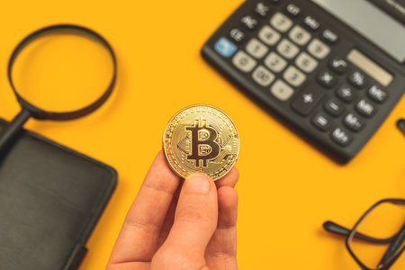 Businessman hold bitcoin in hand on office desk background, crypto currency coin close up
