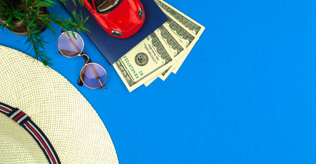 Tropical vacation composition, red car, money and straw hat on blue background, trip and travel...