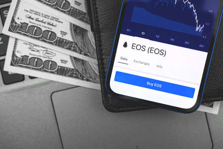 EOS crypto currency on the screen of mobile phone, online banking concept, investment and finance background with wallet and dollarの写真素材