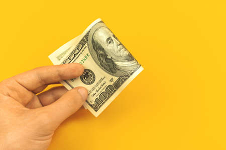 Concept of deposit money, hand with one hundred dollar bill on a yellow background, financeの写真素材
