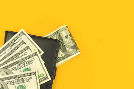 Leather wallet with lots of money, concept of investment with dollar bills, yellow office table background, top view with copy spaceの写真素材
