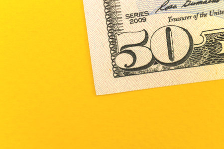 Deposit money with fifty dollar bills, office desktop with yellow background and copy spaceの写真素材