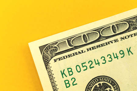 Concept of money deposit with one hundred dollar bill on the office table close-up, yellow backgroundの写真素材